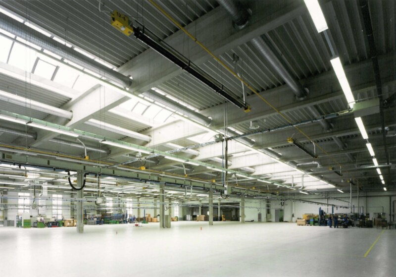 Plynový tmavý infrazářič KM-I instalovaný pod stropem velké průmyslové haly.