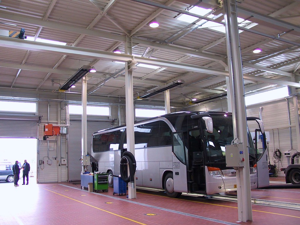 Plynový tmavý infrazářič KM-U instalovaný pod stropem servisní haly pro autobusy. Vysoké tepelné ztráty jsou rozhodujícím faktorem, jestli zvolit sálavé panely nebo plynové infrazářiče
