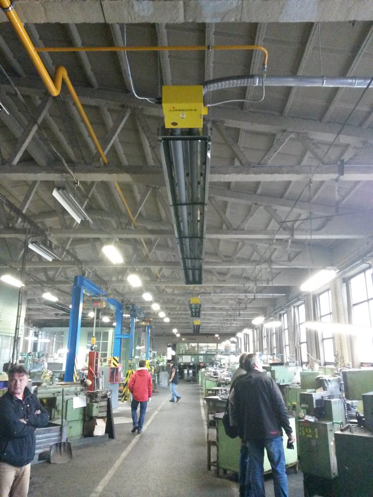 Stropní plynový infrazářič KM-U nad pracovním prostorem ve strojírenské hale.
